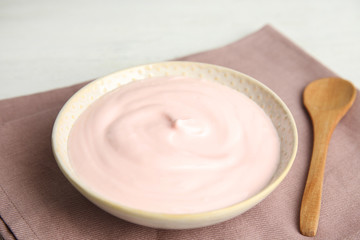 Tasty organic yogurt and spoon on fabric