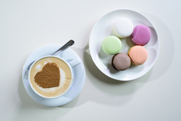 Delicious macaroons and cappuccino on a large bright table in a cozy coffee shop