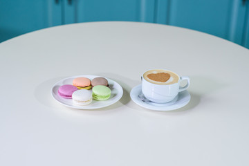 Delicious macaroons and cappuccino on a large bright table in a cozy coffee shop