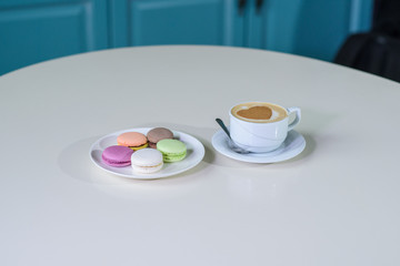 Delicious macaroons and cappuccino on a large bright table in a cozy coffee shop