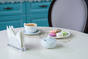 Delicious cappuccino and macaroons prepared on a table for a guest