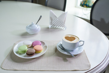 Delicious cappuccino and macaroons prepared on a table for a guest