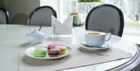 Delicious cappuccino and macaroons prepared on a table for a guest