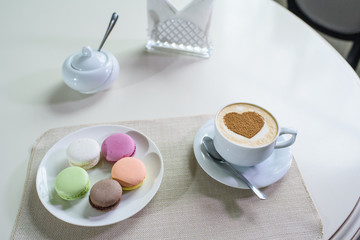 Delicious cappuccino and macaroons prepared on a table for a guest
