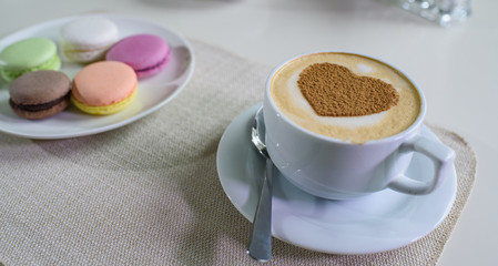 Delicious cappuccino and macaroons prepared on a table for a guest