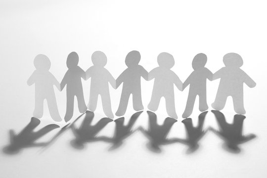 Paper people holding hands on white background. Unity concept