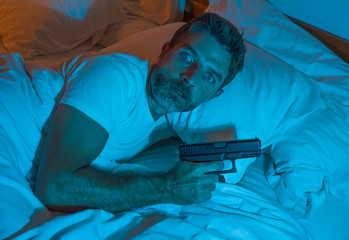 night edgy portrait of young stressed and paranoid American man lying on bed unable to sleep...