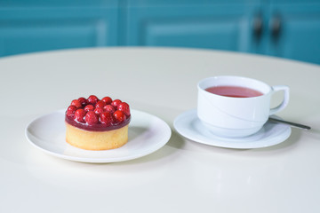 Delicious berry tea and tarte with raspberries on a table in a cozy coffee shop