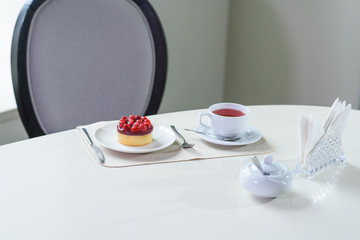 Delicious berry tea and tarte with raspberries prepared on a table for a guest in a cozy cafe