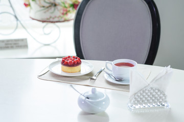 Delicious berry tea and tarte with raspberries prepared on a table for a guest in a cozy cafe