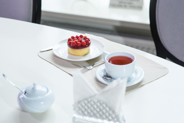 Delicious berry tea and tarte with raspberries prepared on a table for a guest in a cozy cafe