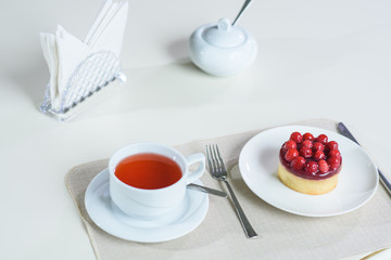 Delicious berry tea and tarte with raspberries prepared on a table for a guest in a cozy cafe