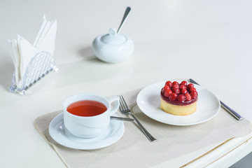 Delicious berry tea and tarte with raspberries prepared on a table for a guest in a cozy cafe