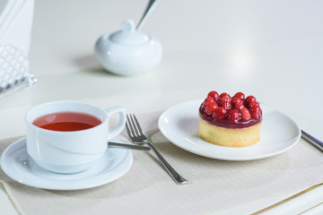 Delicious berry tea and tarte with raspberries prepared on a table for a guest in a cozy cafe