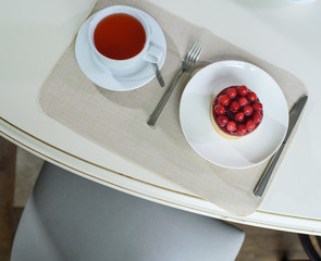 Delicious berry tea and tarte with raspberries prepared on a table for a guest in a cozy cafe