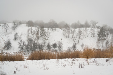 Winter landscape with hills and dark trees. The mountains are covered with snow in the cold season.