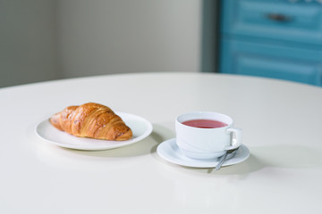 Fruit tea and delicious fresh croissant on the table in a cozy coffee shop