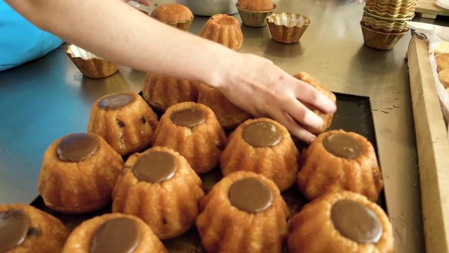 Baker hand taking out cupcakes from molds. Freshly baked pastries with delicate flavor. Manufacture of baking products.