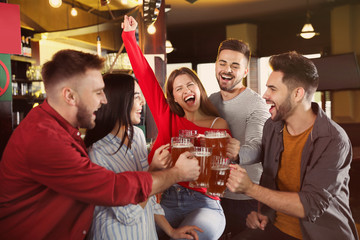 Group of friends celebrating victory of favorite football team in sport bar