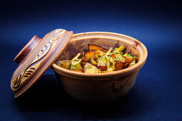 Roasted potatoes with mushrooms and pork on black background
