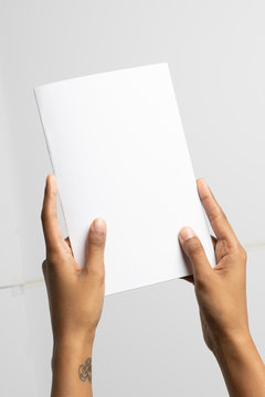 Ethnic woman holding a 5.5"x8.5" mockup brochure or folder. The size is close to A5.