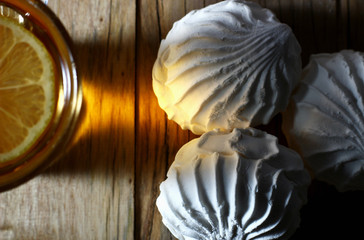 top view of a glass of tea with a slice of lemon and a white marshmallow on the table