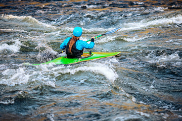 Girl in kayak sails mountain river. Whitewater kayaking, extreme sport rafting