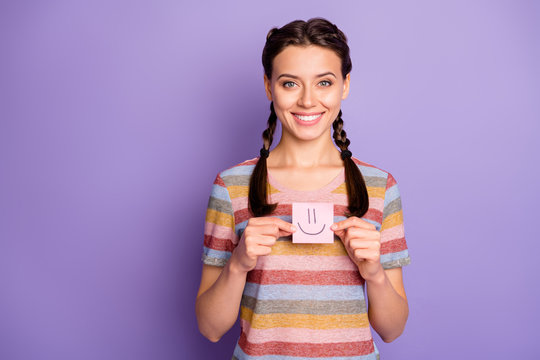 Photo of pretty lady holding paper emoticon good mood showing positive painted emotion wear casual striped t-shirt isolated pastel purple color background