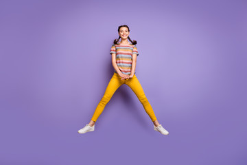 Fototapeta na wymiar Full length photo of funny lady jumping high summer mood excited sunny day warm weather wear casual striped t-shirt yellow trousers isolated purple color background