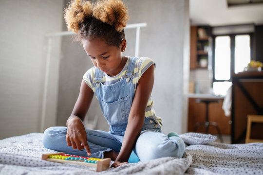 Happy African American Kid Girl Learn To Count At Home With Abacus