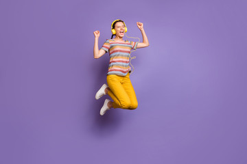Full length photo of funky lady jumping high listening cool earflaps signing crazy youth songs wear...