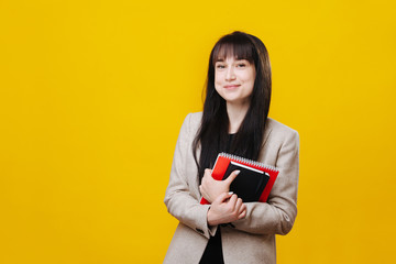 Confident satisfied young business woman in a gray jacket with pair of notebooks