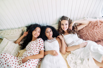 Beautiful multi ethnic girls relax together and lying on bed inside the camper van