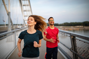 Early morning workout. Happy couple running across the bridge