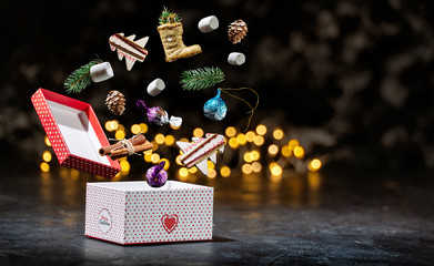 Christmas composition of surprise boxes decorated with shiny ribbons, red Christmas balls, clock and fir cones on a red background. Winter Christmas and New Year holiday banner