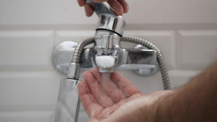 Man Opening Bathroom Faucet and Cleaning His Hands with Water