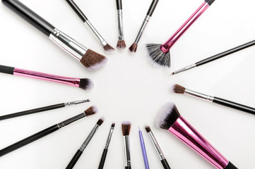 Circle of professional makeup brushes over white background