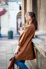 Stylish girl on a walk in the street. Beige raincoat, bag over his shoulder. Image of a modern woman
