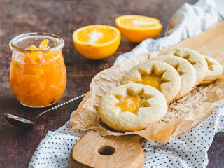 Fresh, fragrant handmade cookies, lying on a cutting board and jam of orange slices. Close-up, side view. Tasty and healthy eating concept