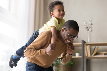 Smiling preschooler boy piggyback playing with dad