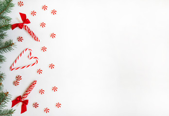 Christmas composition. Fir branches and candy cane on white background. Flat lay, top view, copy space.