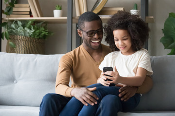 Obraz premium Happy black dad hug daughter using smartphone together