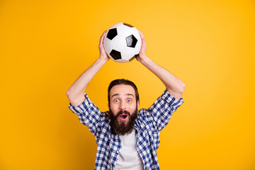 Portrait of nice attractive cheerful cheery funky addicted bearded guy fan in checked shirt holding in hands over head ball having fun isolated over bright vivid shine vibrant yellow color background