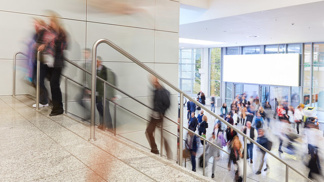 Viele Leute auf Treppe vor Webeplakat auf Messe