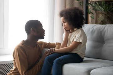 Supportive black dad talk cheering sad preschooler daughter