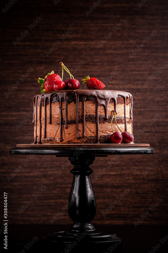 Wall mural Chocolate cake with with berries, strawberries and cherries. cake on a dark brown background. copy space