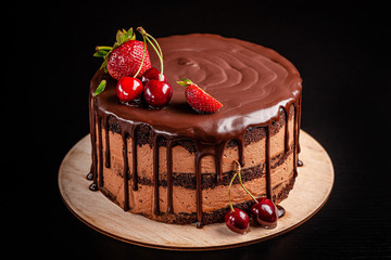 Chocolate cake with with berries, strawberries and cherries. cake on a dark brown background. copy space
