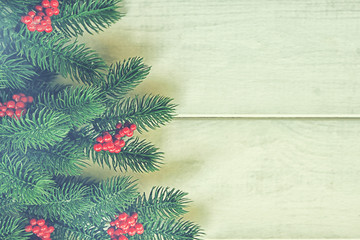 Christmas decoration with fir branches and red berries on a rustic wooden background. Christmas, winter, new year concept. Flat lay, top view, copy space.