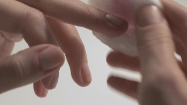 Girl removing nail polish from fingers &ndash; close up shot
