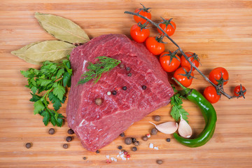 Top view of uncooked beef among vegetables, greens and spices